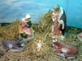 The baby Jesus resting on hay between an ass and and ox and with his parents looking on. 
